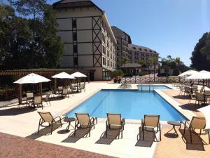 a pool with chairs and umbrellas next to a building at Apart Vista Azul - hospedagem nas montanhas in Domingos Martins +27 photos