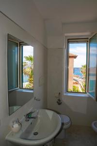 a bathroom with a sink and a toilet and a mirror at B&B del Porto in Bosa Marina