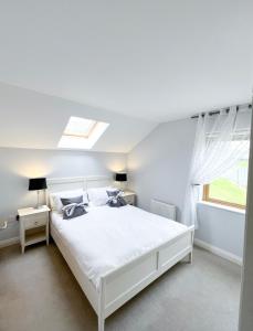 a white bedroom with a white bed and a window at Barleycove Villa, Goleen, West Cork in Goleen