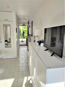 a white kitchen with a flat screen tv on a counter at Studio Golfe Juan, plages, parking, climatisation in Vallauris