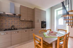 a kitchen with wooden cabinets and a table and chairs at La TERRAZZA sul GIARDINO in Procida