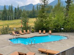 a swimming pool with chairs and tables and a mountain at Snow Creek Lodge by Fernie Central Reservations in Fernie