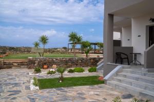 a house with a stone retaining wall and a patio at Lafo Rooms in Elafonisi