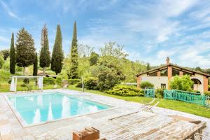 een zwembad in een tuin met een huis bij Villa Il Fornacino in Rapolano Terme