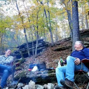 dwóch mężczyzn siedzących w fotelach obok strumienia w obiekcie Loblolly Pines Adventure Aframe #2 w mieście Eureka Springs