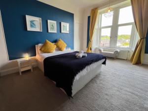 um quarto com uma cama grande e uma parede azul em A Spacious Flat with Character - Private Car Space em Paisley