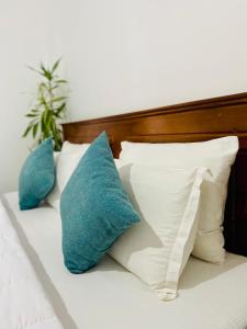 Una cama con almohadas blancas y azules. en Highest Village Bungalow, en Nuwara Eliya