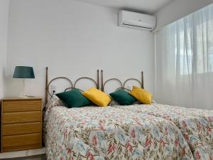 um quarto com uma cama com almofadas amarelas e verdes em Modern apartment on the beach with pool em Calpe