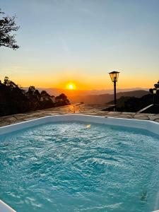 a hot tub with the sunset in the background at Pousada Village Pôr do Sol in Campos do Jordão