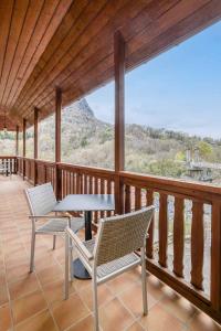 - une terrasse couverte avec 2 chaises et une table sur un balcon dans l'établissement Auberge du pont de l'Abîme, à Gruffy