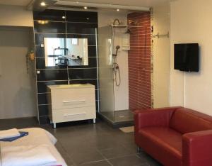 a bathroom with a sink and a shower and a couch at Studio Village Naturiste vue mer HELIOPOLIS C in Cap d'Agde