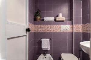 a purple bathroom with a toilet and a sink at Dulcis In Colosseo Apartments in Rome