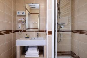 a bathroom with a sink and a shower at Hôtel de Lion sur Mer in Lion-sur-Mer
