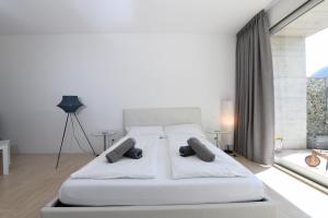 a white bedroom with a large white bed with pillows at The Minimal House & SPA in Caslano