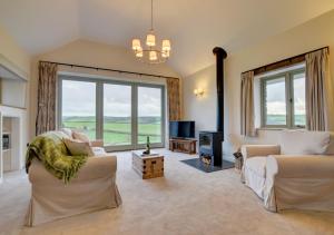 a living room with a couch and a tv and windows at Barton Barn in Bishops Nympton