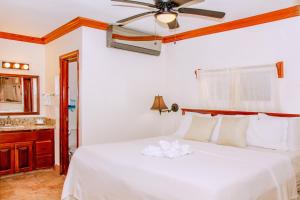 a bedroom with a white bed with a ceiling fan at Mayan Princess Hotel in San Pedro