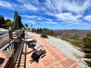 een groep banken op een balkon met uitzicht op de bergen bij Casa Delfin: Luxurious villa with heated pool & mountain views in Cómpeta