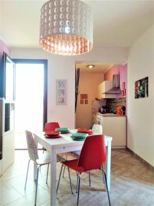 a dining room with a white table and red chairs at CASE COLOMBO E MATTARELLA- Appartamenti centrali con wi-fi e parcheggio privato gratuito in San Vito lo Capo