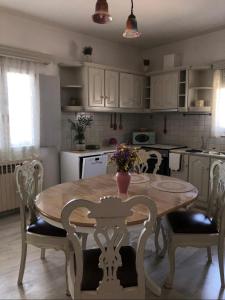 una cucina con tavolo e sedie in legno e una cucina con armadietti bianchi di FYKIA HOUSE a Naoussa