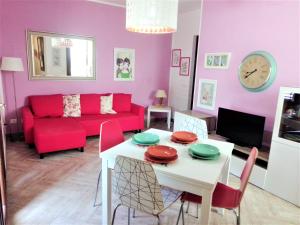 a living room with a table and a red couch at CASE COLOMBO E MATTARELLA by TreRose Properties - Appartamenti centrali con wi-fi e parcheggio privato gratuito in San Vito lo Capo