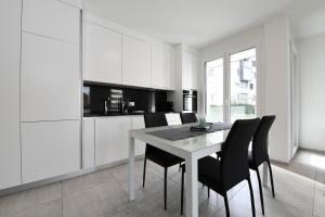 uma cozinha branca com uma mesa e cadeiras pretas em Ascona for Two em Ascona