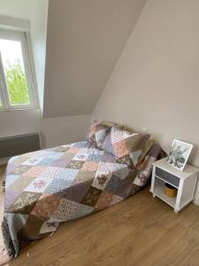 1 dormitorio con 1 cama con edredón y mesa en Studio lumineux de 35m2 au cœur de Solesmes en Solesmes