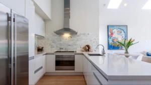 a kitchen with white cabinets and a stainless steel refrigerator at The Richmond Cottage in Melbourne