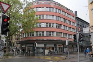 een hoog rood gebouw in een stadsstraat met een verkeerslicht bij Stay2Night City Center Hostel in Zürich