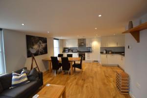 a living room with a couch and a table and a kitchen at Queens House 2 bed City Centre Apartment - STAYSEEKERS in Salisbury