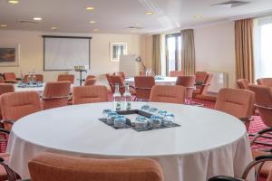 una sala de conferencias con mesas, sillas y una pantalla en Hampshire Court Hotel & Spa, en Basingstoke