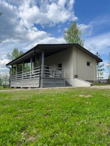 a small building with a porch and a grass field at Atpūtas namiņš Jaunlaicenē in Jaunlaicene