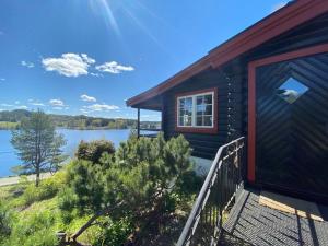 a house with a deck with a view of a lake at Lakefront Cabin in Magnor