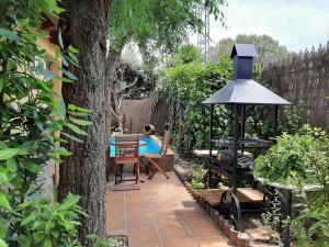 un giardino con albero, tavolo e ombrellone di Acogedora casa rural en la sierra de Madrid a Mataelpino