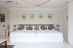 a white bedroom with a white bed with blue pillows at Nichahome Luxury Villa in Hua Hin