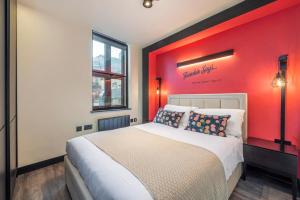 sypialnia z dużym łóżkiem z czerwoną ścianą w obiekcie The Influencer Suite - Soho - by Frankie Says w Londynie