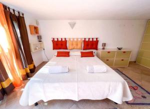 una camera da letto con un grande letto bianco con cuscini arancioni di Hibryd: in centro, a due passi dal mare a Oristano
