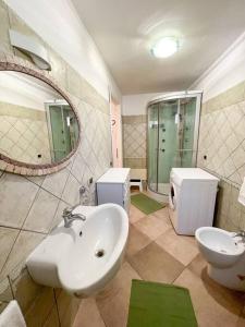 een badkamer met een wastafel, een toilet en een spiegel bij Hibryd: in centro, a due passi dal mare in Oristano