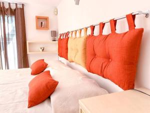 una cama con almohadas naranjas en una habitación en Hibryd: in centro, a due passi dal mare, en Oristano