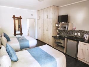 a hotel room with two beds and a tv at Tramonto Lodge in Upington