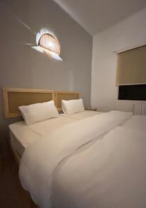 - une chambre avec 2 lits avec des draps blancs et une lumière dans l'établissement Crafthouse, à Amman