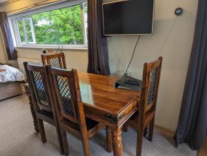 a wooden table with two chairs and a television on a wall at Bristol self-catering studio+kitchen+parking in Bristol