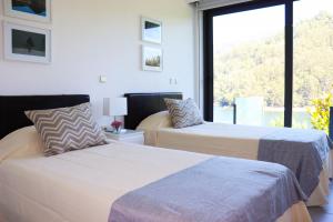 2 Betten in einem Zimmer mit einem großen Fenster in der Unterkunft Apartamento Javali - Casas Barca do Rio - Geres in Geres