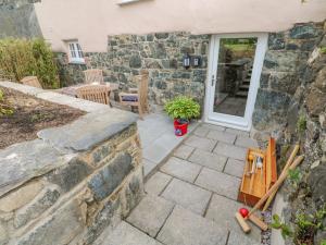 a patio with a stone wall next to a house at Gilly Skyber in Helston