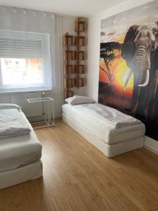 マンハイムにあるJoanna Apartment - MA Käfertal 1のベッドルーム1室(ベッド2台付)が備わります。象の壁画が飾られています。