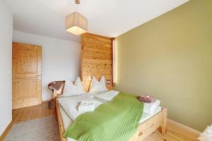 a bedroom with a bed with a green blanket at Ferienwohnungen Zwick Maroles in Malles Venosta