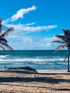 uma pessoa a caminhar numa praia com palmeiras em Suspiro da Bahia Pé na areia em Salvador