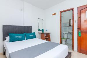 1 dormitorio con cama blanca y almohadas azules en Ayenda Confort De La Guajira, en Ríohacha