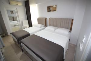 a bedroom with two beds and a mirror at Pegasus Motel in Avşa Adası +9 photos