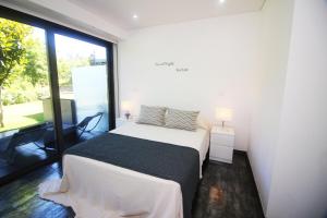 a bedroom with a bed and a large window at Apartamento Garrano - Casas Barca do Rio by Gerês Casas in Geres