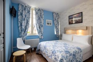 1 dormitorio con paredes azules, 1 cama y 1 silla en Hôtel de Lion sur Mer, en Lion-sur-Mer